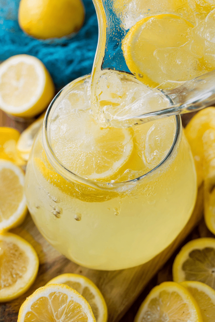Glass of homemade lemonade garnished with lemon slice and mint on a wooden table.