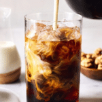 Refreshing iced coffee in a glass with straw on a wooden table, perfect for a warm day.