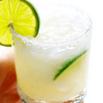 Refreshing margarita in a salt-rimmed glass with a lime wedge against a summer backdrop.
