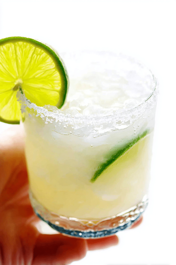 Refreshing margarita in a salt-rimmed glass with a lime wedge against a summer backdrop.