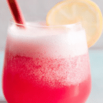 Rhubarb gin fizz cocktail with lemon twist garnish surrounded by fresh rhubarb and gin bottle