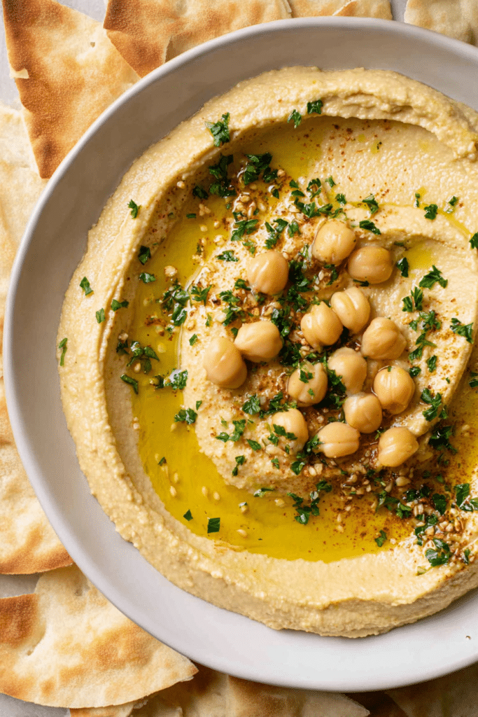 Delicious roasted garlic hummus with olive oil, parsley, and chickpeas, served with pita bread.