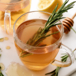 A warm cup of rosemary tea beside fresh rosemary sprigs, perfect for a cozy drink experience.
