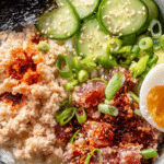 Spicy Tuna Sushi Bowl with crispy rice, cucumber, and scallions on a wooden table.