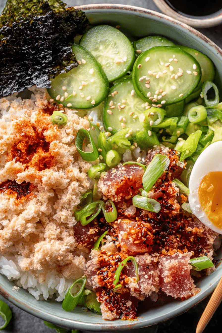 Spicy Tuna Sushi Bowl with crispy rice, cucumber, and scallions on a wooden table.