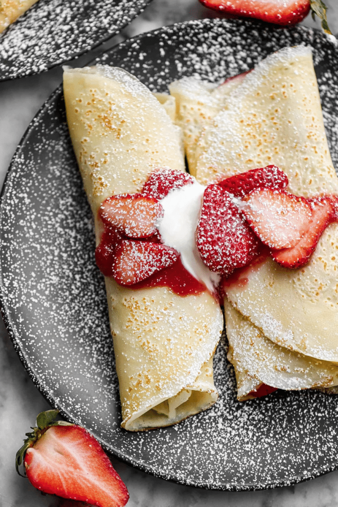 Delicious strawberry crepes with fresh strawberries and whipped cream, perfect for breakfast or dessert.