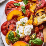 Tomato peach burrata salad with heirloom tomatoes and peaches on a wooden table