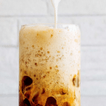Vanilla sweet cream cold foam served over coffee in a clear glass, highlighting the creamy texture and layers.