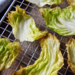 Close-up of baked crispy cabbage chips served on a plate, showcasing their crunchy texture and golden brown edges.