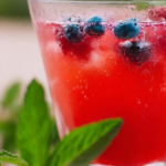 Refreshing blueberry raspberry iced tea cooler with fresh berries and lemon slices on a sunny table.