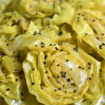 Bowl of cabbage in mild yogurt and mustard seed curry garnished with cilantro and served with rice.
