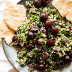 Cherry tabbouleh salad served in a colorful bowl, topped with fresh herbs and drizzled with olive oil.