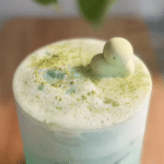 Layered Coconut Matcha Cloud drink with coconut water and matcha cold foam, garnished with coconut slice.