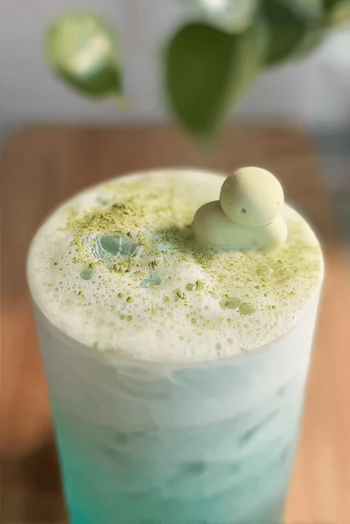 Layered Coconut Matcha Cloud drink with coconut water and matcha cold foam, garnished with coconut slice.