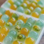 Colorful fruit jelly dessert with fresh chopped fruits including strawberries, kiwi, and mango.