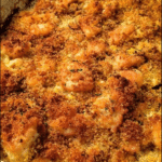 Close-up of cornbread-cabbage casserole with melted cheese on top, served in a rustic dish.