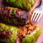 Delicious homemade easy cabbage rolls with bacon topping on a serving plate.