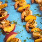 Delicious grilled shrimp and peach kabobs garnished with herbs on a rustic wooden table.