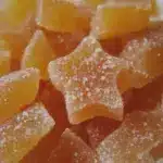 Delicious homemade peachy gummies served on a plate with fresh peach slices and mint.