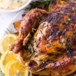 Lemon herb roasted chicken with crispy skin and fresh herbs on a wooden table