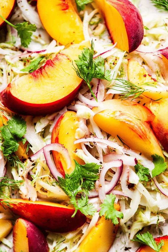 Nectarine and fennel salad with almonds and herbs on a white plate