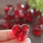 Close-up of homemade pomegranate gummies with fresh pomegranates and mint leaves on a wooden table.