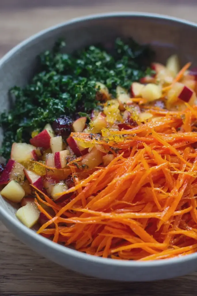 A colorful salad made with shredded carrots, diced nectarines, and garnished with cilantro and cashews in a bowl.
