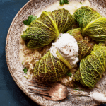 Close-up of stuffed cabbage rolls filled with rice and garnished with sour cream and herbs