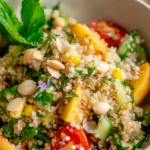 Fresh summer quinoa salad with nectarines, cucumbers, cherry tomatoes, corn, and herbs in a bowl.