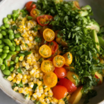 A colorful summer succotash with grilled corn, cherry tomatoes, and herbs served in a bowl