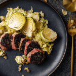 Tenderloin steak with truffle butter served with pointed cabbage and artichokes on a fine dining table.