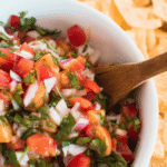 Vibrant bowl of lacto fermented salsa with fresh tomatoes, bell peppers, and cilantro on a wooden table.