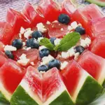 Colorful watermelon feta and blueberry salad in a bowl with fresh mint leaves, perfect for summer gatherings.
